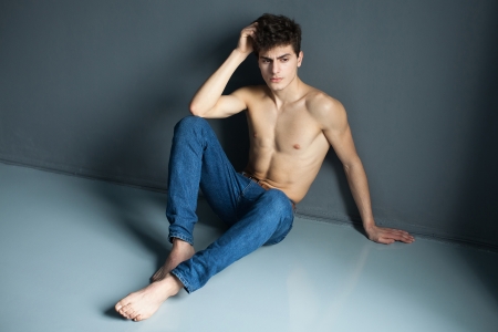 Portrait of a well built shirtless muscular male model sitting on the floorの写真素材