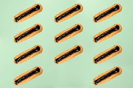 Flat lay with arranged homemade eclairs with chocolate ganache isolated on greenの写真素材
