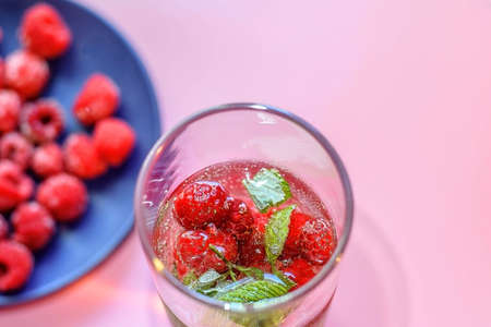 Refreshing summer drink with fresh raspberries and mint on a pink backgroundの写真素材
