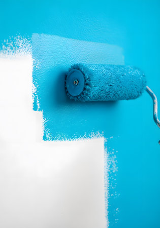 Paint roller on a blue wall, painting the walls with blue paintの素材