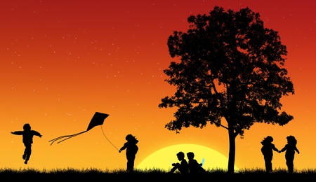Silhouettes of children playing in grass with treeの写真素材