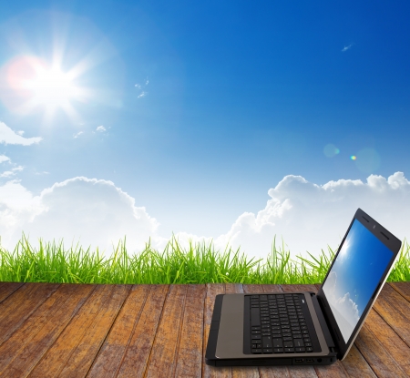 Laptop on wood floor with green grassの写真素材