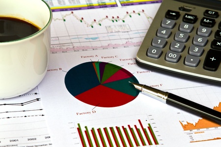 Various financial charts on the table with calculator, coffee and penの写真素材