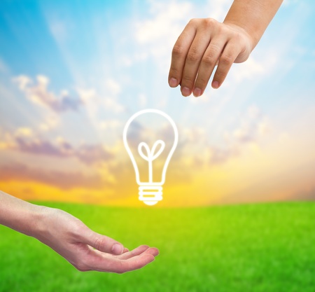 From hand to hand the light bulb as a symbol of Idea.の写真素材