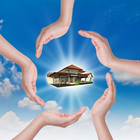 The house in human hand over blue skyの写真素材