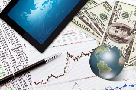 Business graph,touchpad, pen,earth and dollars on tableの写真素材