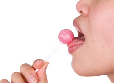 Woman licking a pink shiny lollipop on white background.の写真素材