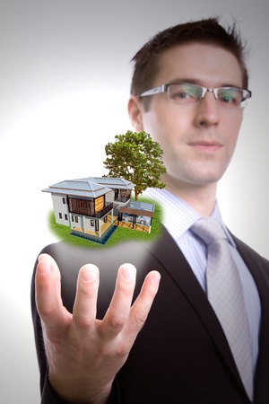 Portrait of young business man holding houseの写真素材