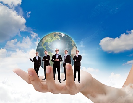Young business man team in hand and earth over blue skyの写真素材
