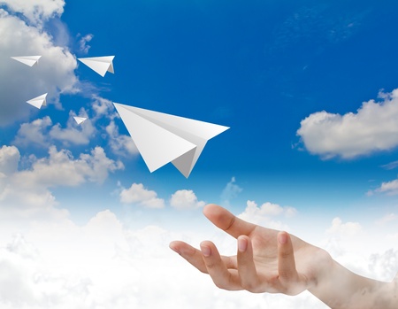 Hand throwing a paper plane in the skyの写真素材