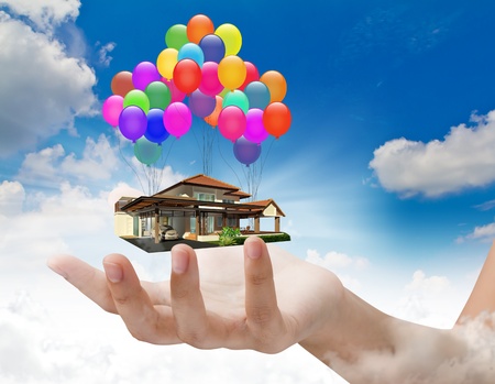 A house lifted by Balloons on handの写真素材