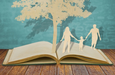 Paper cut of family symbol under tree on old bookの写真素材