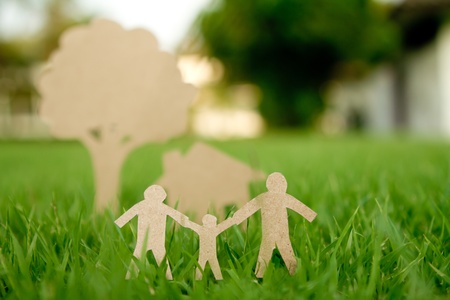 Paper cut of family with house and tree on fresh spring green grassの写真素材