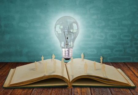 Paper cut of business people and light bulb on bookの写真素材