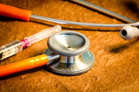 Medical stethoscope and syringe over brown backgroundの写真素材
