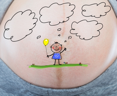 Pregnant woman with the painted  of her baby thinking of future written on her belly.の写真素材