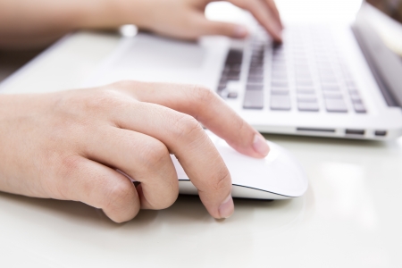 Closeup of business woman hand typing on laptop keyboard with mouseの写真素材
