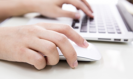 Closeup of business woman hand typing on laptop keyboard with mouseの写真素材