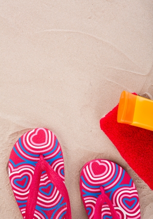Flipflops ,sunscreen,towel on sand beachの写真素材