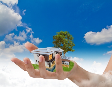 The house in human hand over blue skyの写真素材