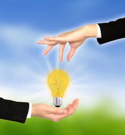 light bulb between two handsの写真素材