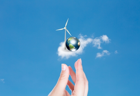 Wind turbines and earth with hand over blue sky の写真素材