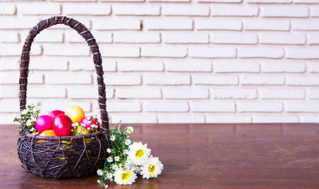 Colorful easter eggs in brown basket with flower
