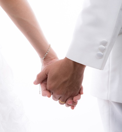 Closeup of  bride and groom holding hands isolated on white backgroundの写真素材
