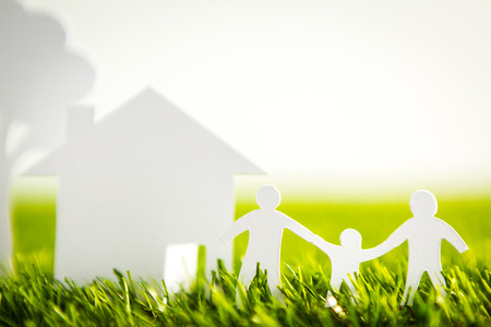 Paper cut of family with house and tree on fresh spring green grassの写真素材