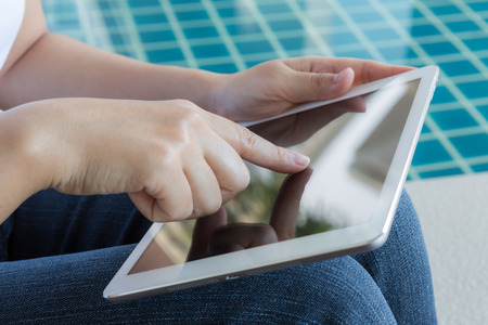 Woman working with tablet sitting at swimming poolの写真素材
