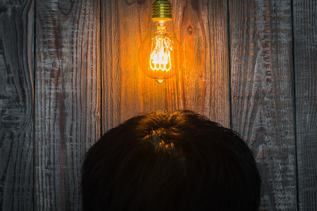 Head with Glowing bulb on the wood backgroundの写真素材