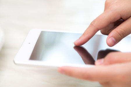 Woman hand touch white tablet with blank empty screen