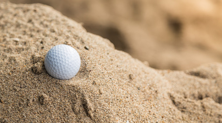 Golf ball in sand bunkerの写真素材