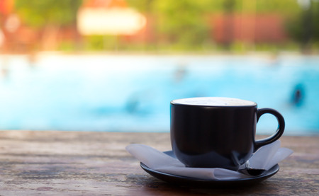 Cup of coffee on wooden deck near Swimming poolの写真素材