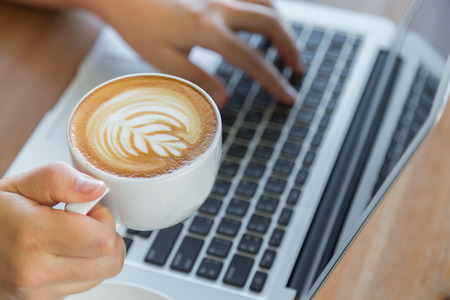 Closeup of business woman hand typing on laptop keyboard and coffeeの写真素材