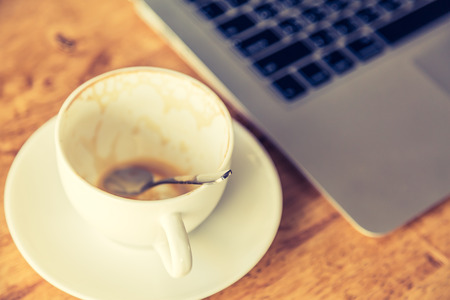 Empty coffee cup and laptop on old wooden table ( Filtered image processed vintage effect. )の写真素材