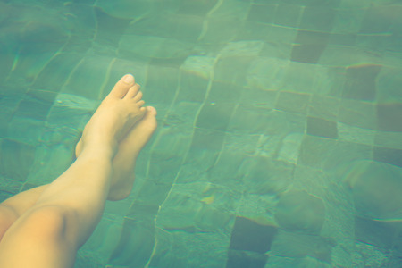 Female legs under the swimming pool waterの写真素材