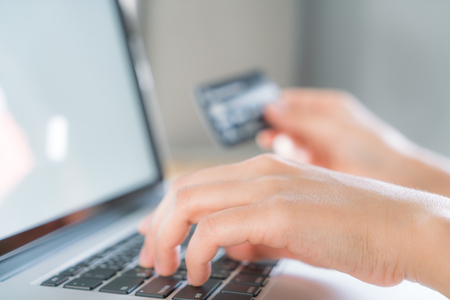 Hands holding a credit card and using laptop computer for online shoppingの写真素材