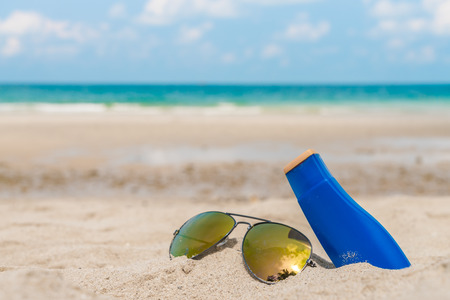 Sunglasses and sun cream on white  sand beachの写真素材