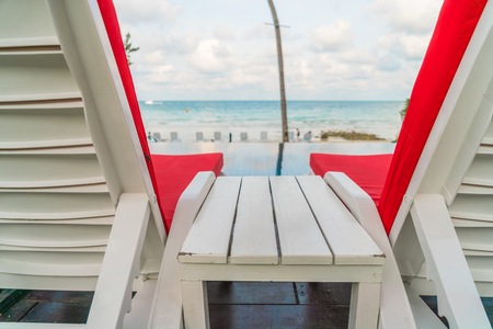 Beautiful beach chairs with umbrella around outdoor swimming pool neary sand and seaの写真素材