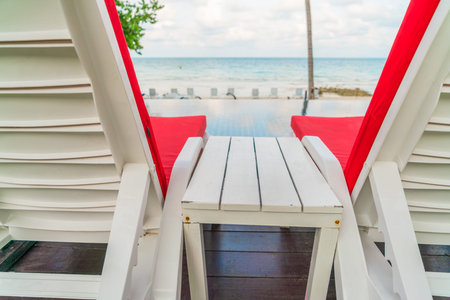 Beautiful beach chairs with umbrella around outdoor swimming pool neary sand and sea