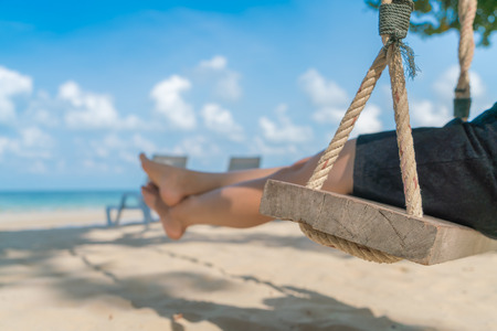 Woman leg on a swing at tropical sea beachの写真素材