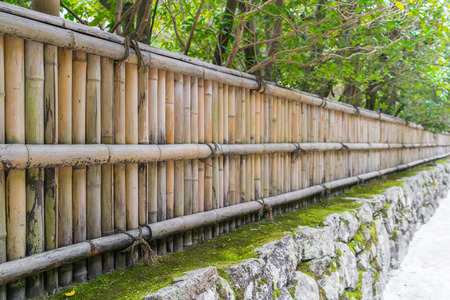 Bamboo fence on stone with green leavesの写真素材
