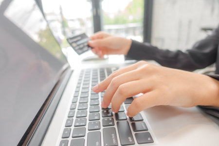 Hands holding a credit card and using laptop computer for online shopping