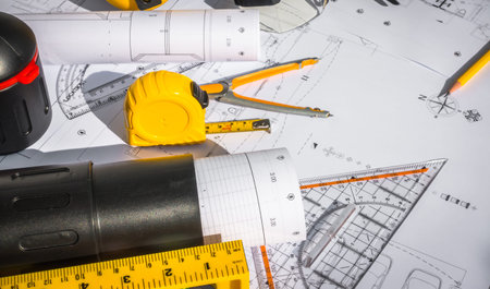 Construction plans with White helmet and drawing tools on blueprints