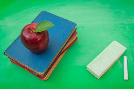 Green blank chalkboard with red apple and bookの写真素材
