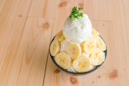 Korean style bing su fresh banana shaved ice on wood tableの写真素材