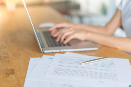 Business woman hand with Financial charts and laptop on the tableの写真素材