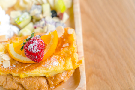 French toast with powdered sugar and a strawberry on wood tableの写真素材