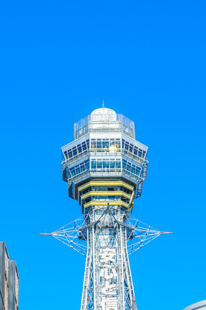 OSAKA, JAPAN - NOVEMBER 30, 2015: Tsutenkaku Tower in Shinsekai (new world) district with blue sky. It is a tower and well-known landmark of Osaka, Japan and advertises Hitachi.のeditorial素材